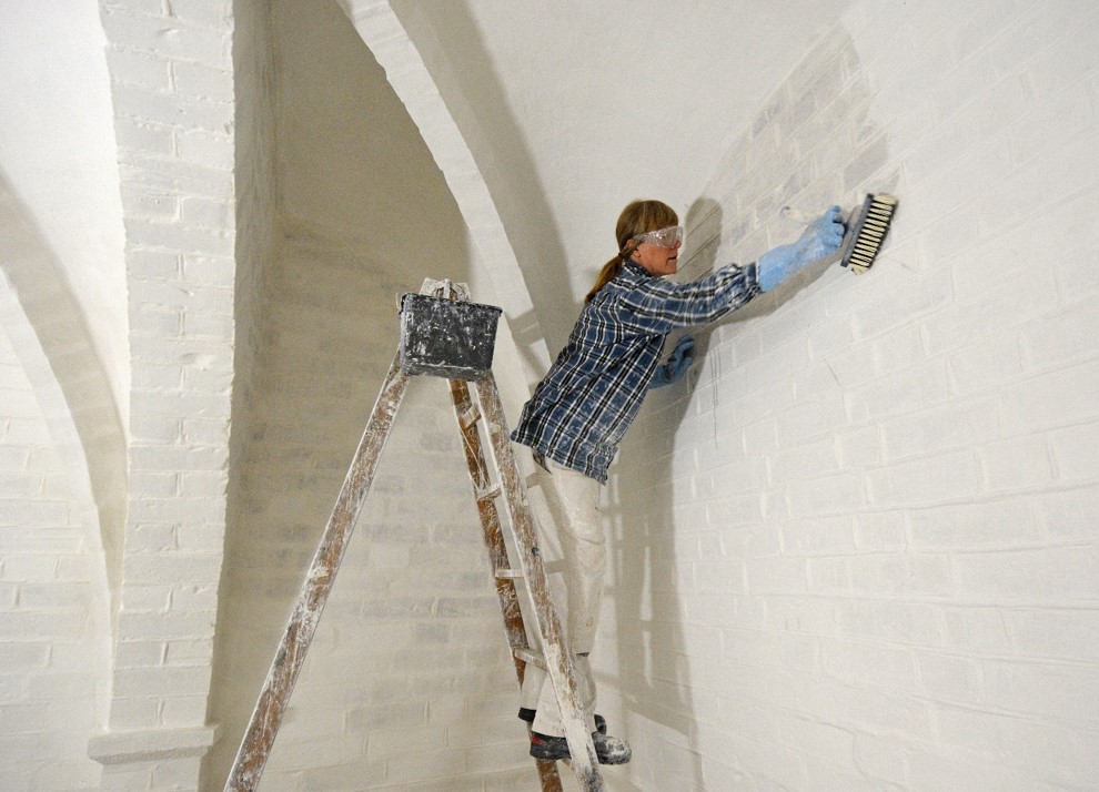 Malersvend Dorthe Kristensen i færd med at kalke kirkerummet
