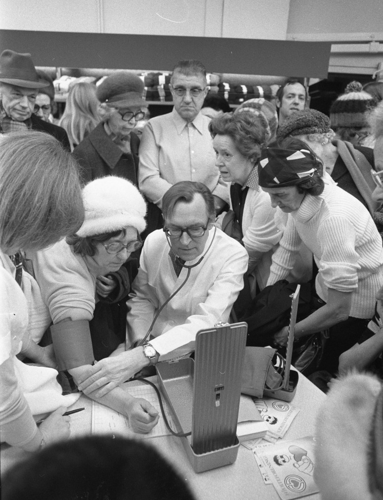 Overlæge på Aarhus Kommunehospital, Poul Ottosen, undersøger blodtryk og hjerter på handlende i Brugsen. 1975. Foto: Hans Bølcho