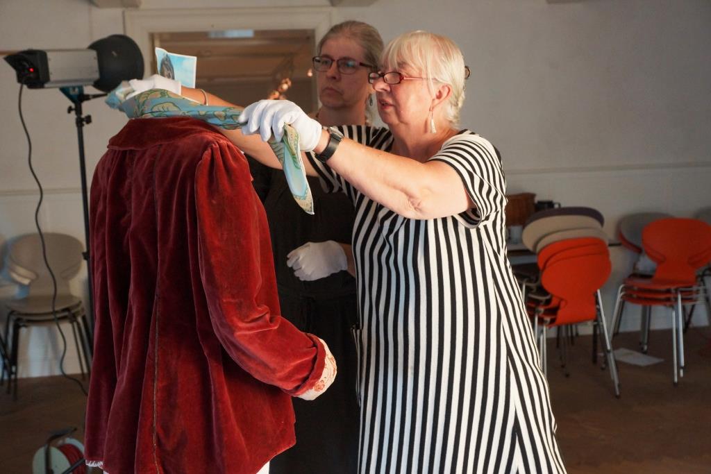 Museumsassistent Karen Flaskgaard monterer et tørklæde.